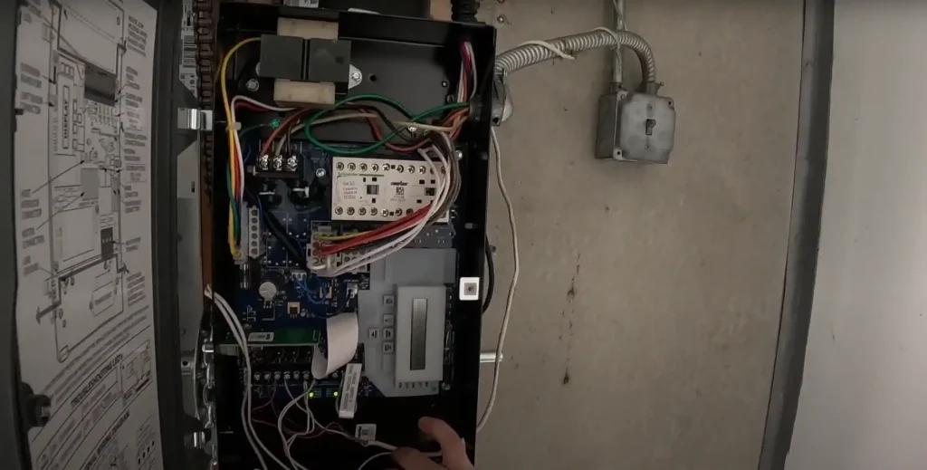 Close-up of the internal wiring and components of a commercial garage door opener being installed, showcasing detailed electrical connections.