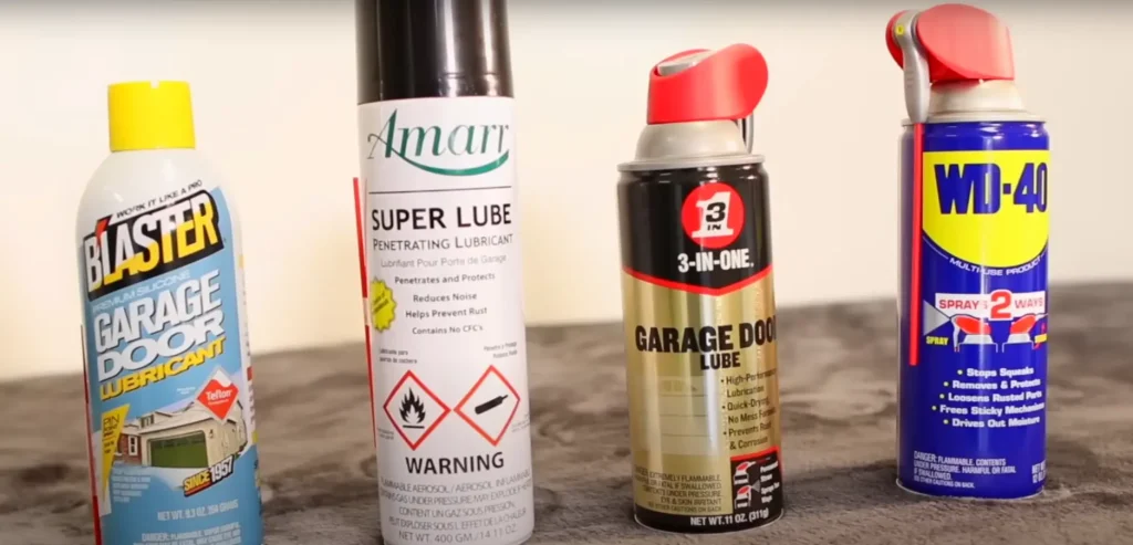 Four different garage door lubricants displayed side by side, including Blaster Garage Door Lubricant, Amarr Super Lube, 3-In-One Garage Door Lube, and WD-40.