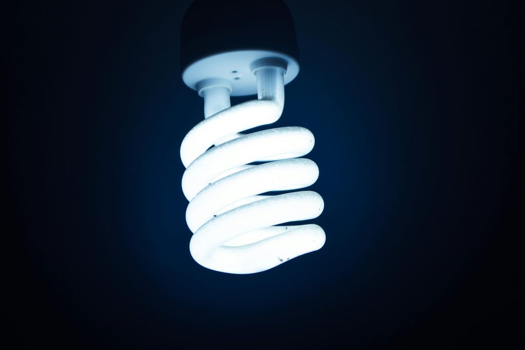 Close-up of an energy-efficient spiral CFL light bulb glowing in the dark.