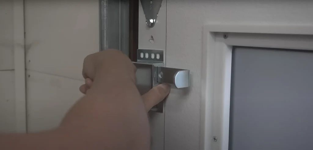 Person adjusting the manual lock on a commercial garage door for added security.
