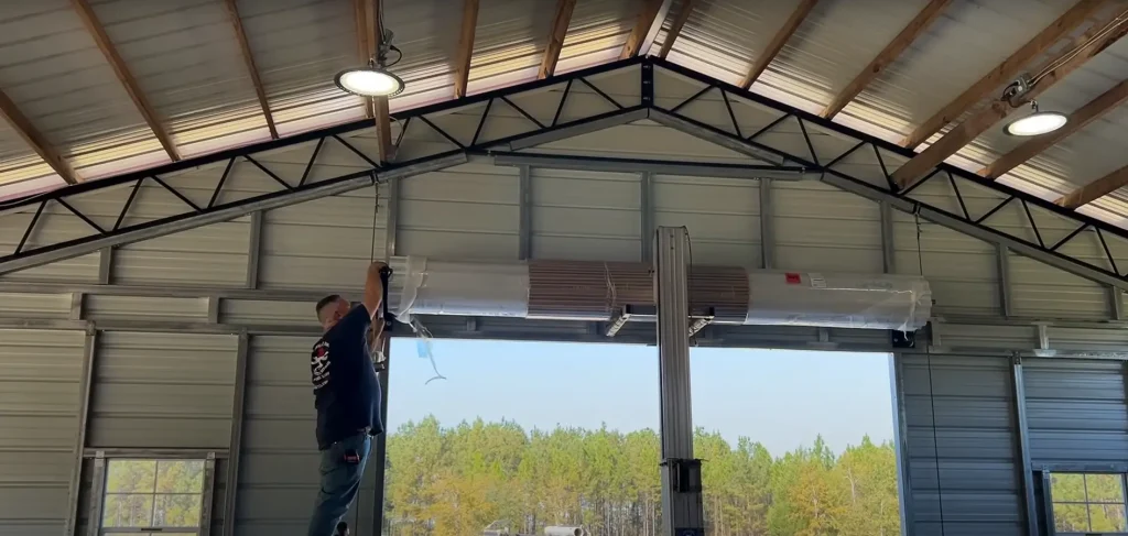 A technician installing a commercial garage door system inside a metal building, ensuring proper alignment and safety compliance.